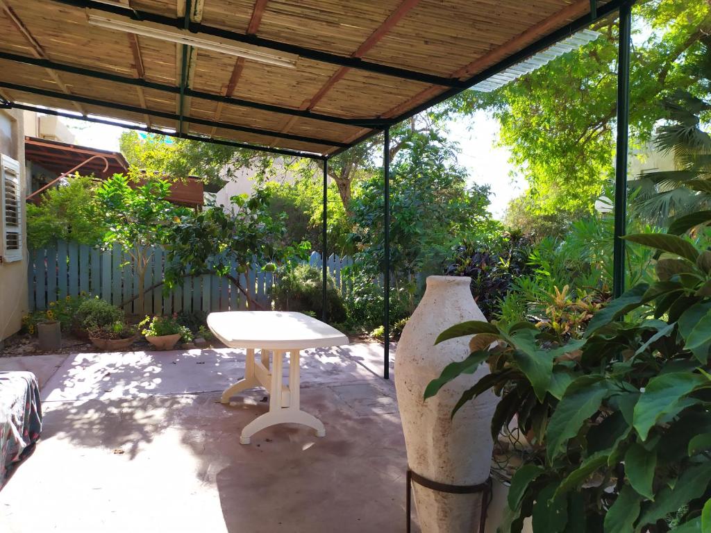 une terrasse avec une table blanche et un grand vase dans l'établissement Ein Gedi Family Apartment, à Ein Gedi