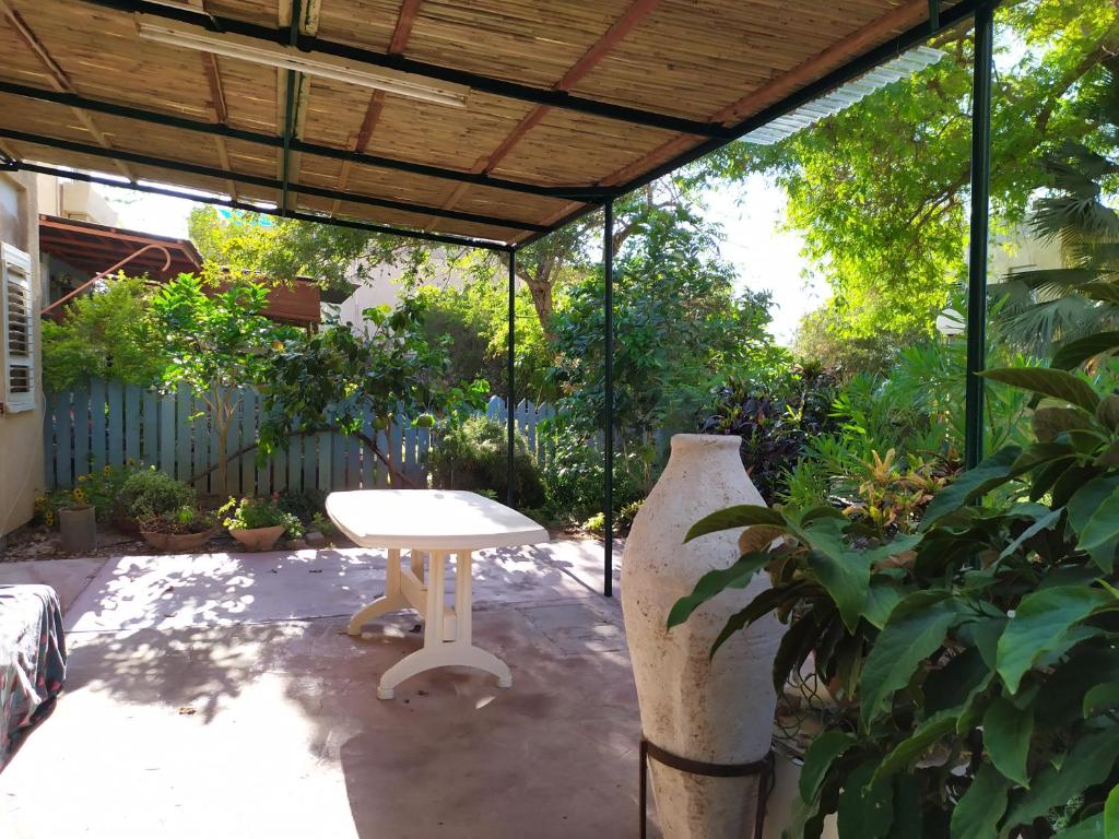 a patio with a white table and a large vase at Ein Gedi Family Apartment in Ein Gedi