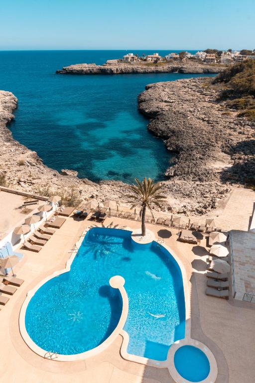 a swimming pool next to a beach with the ocean at Portomar Apartments - 4-Star Superior Hotel in Portocolom