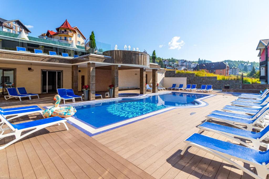 uma piscina com espreguiçadeiras ao lado de uma casa em MARION SPA - Breakfast included in the price Spa Swimming pool Sauna Hammam Jacuzzi Salt room Children's room Restaurant Parking 400 m to Bukovel Lift 1 Mountain view em Bukovel