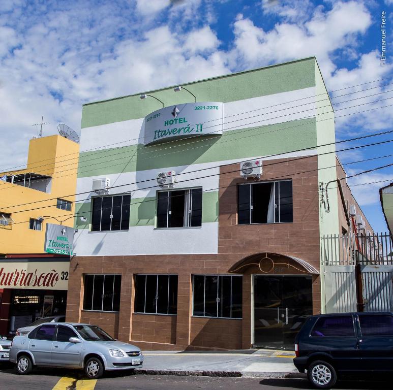 un edificio con coches estacionados frente a él en Hotel Itavera II en Presidente Prudente