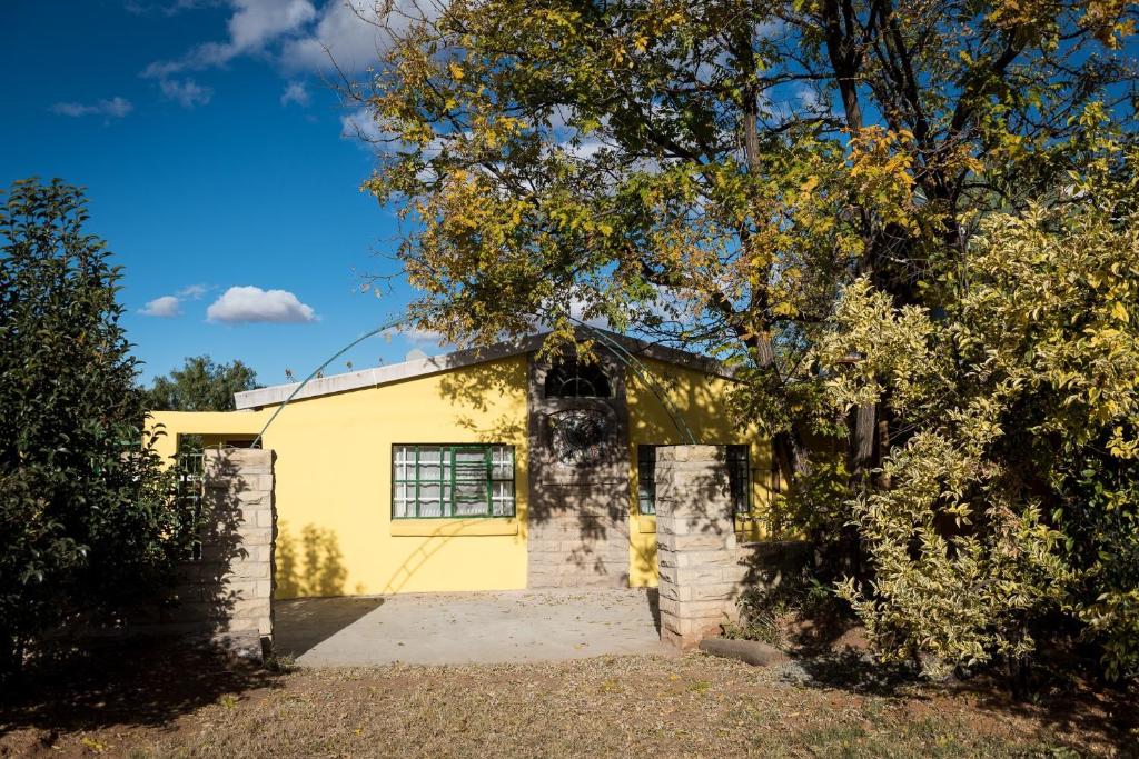 une maison jaune avec un arbre devant elle dans l'établissement Artists cottage, à Ladybrand