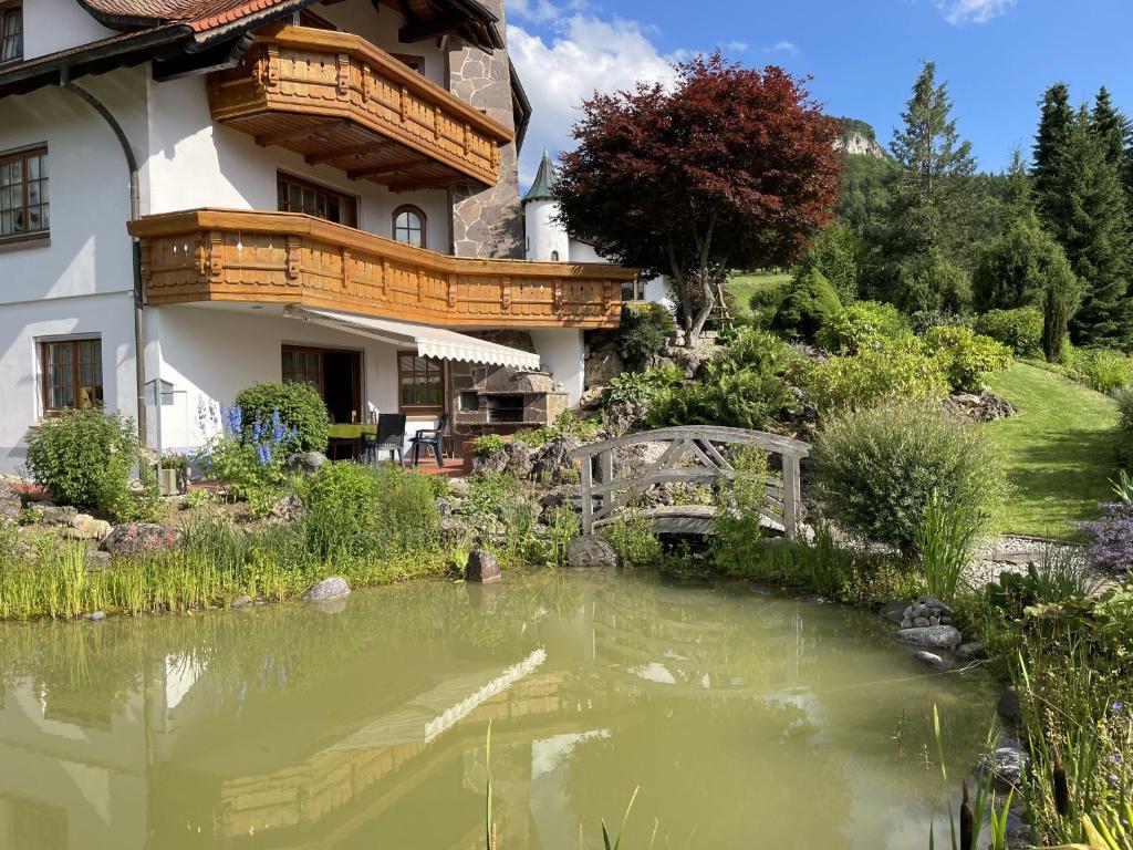 un étang en face d'une maison avec un pont dans l'établissement Ferienwohnung am Steinbach, à Albstadt