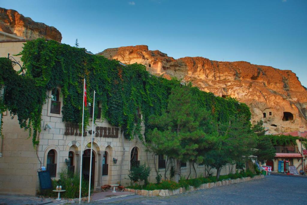 a building covered in ivy next to a mountain at Hotel Surban - Special Category in Ürgüp