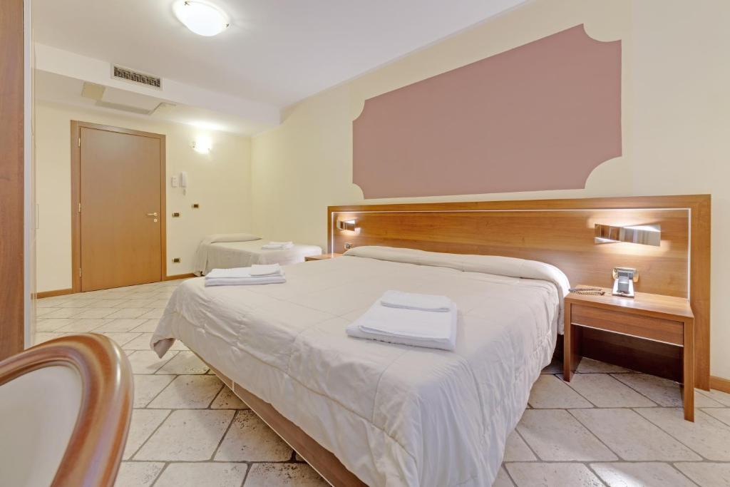 a bedroom with a large bed with a wooden headboard at Hotel Grotto Bagat in Lavena Ponte Tresa