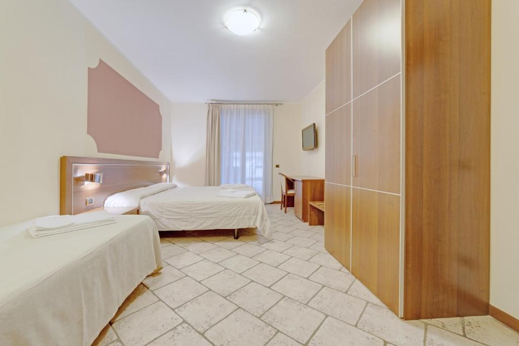 a hotel room with two beds and a bathroom at Hotel Grotto Bagat in Lavena Ponte Tresa