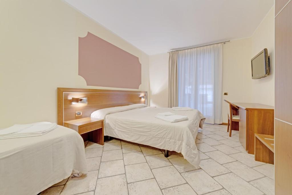 a hotel room with two beds and a window at Hotel Grotto Bagat in Lavena Ponte Tresa