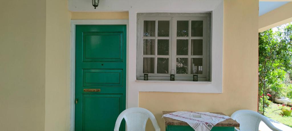 a green door of a house with a table and chairs at Manto House - Amalia Apartment in Káto Figália