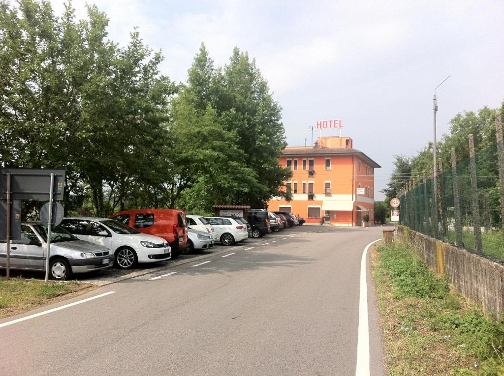 une rangée de voitures garées sur le côté d'une route dans l'établissement Hotel Green castellani, à Vicence