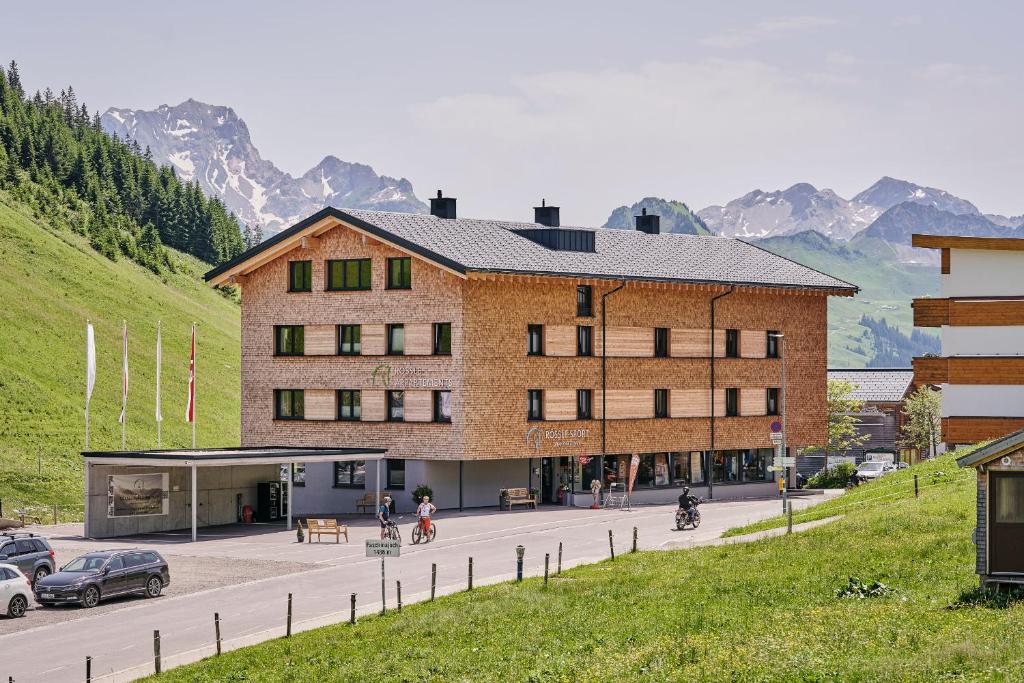 ein großes Gebäude mit Autos auf einem Parkplatz in der Unterkunft Rössle Appartements in Faschina