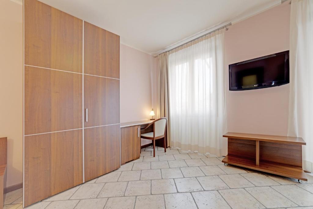 a room with a desk and a tv on a wall at Hotel Grotto Bagat in Lavena Ponte Tresa
