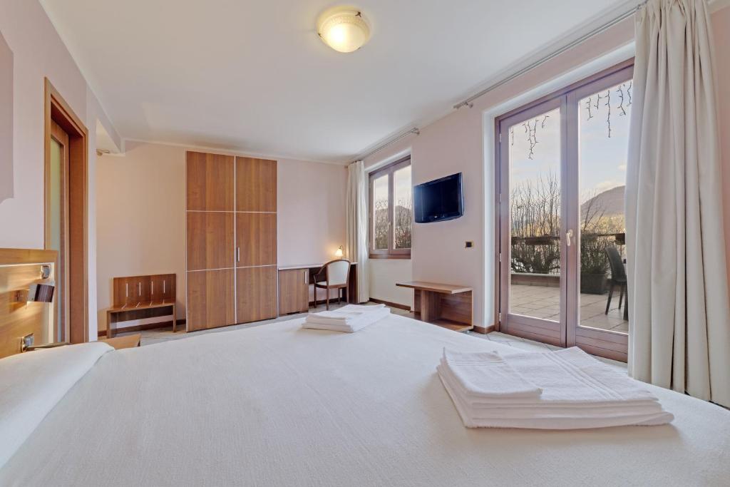 a bedroom with a large bed and a large window at Hotel Grotto Bagat in Lavena Ponte Tresa