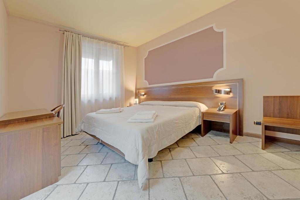 a bedroom with a large bed and a wooden headboard at Hotel Grotto Bagat in Lavena Ponte Tresa