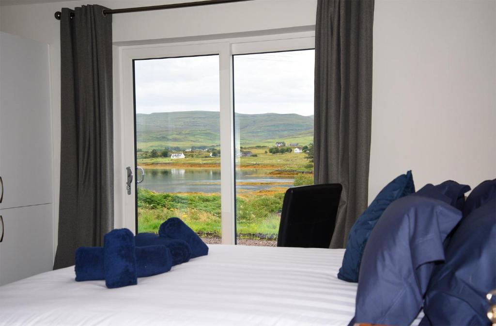 a bedroom with a bed and a large window at Treaslane Bridge House in Kensaleyre