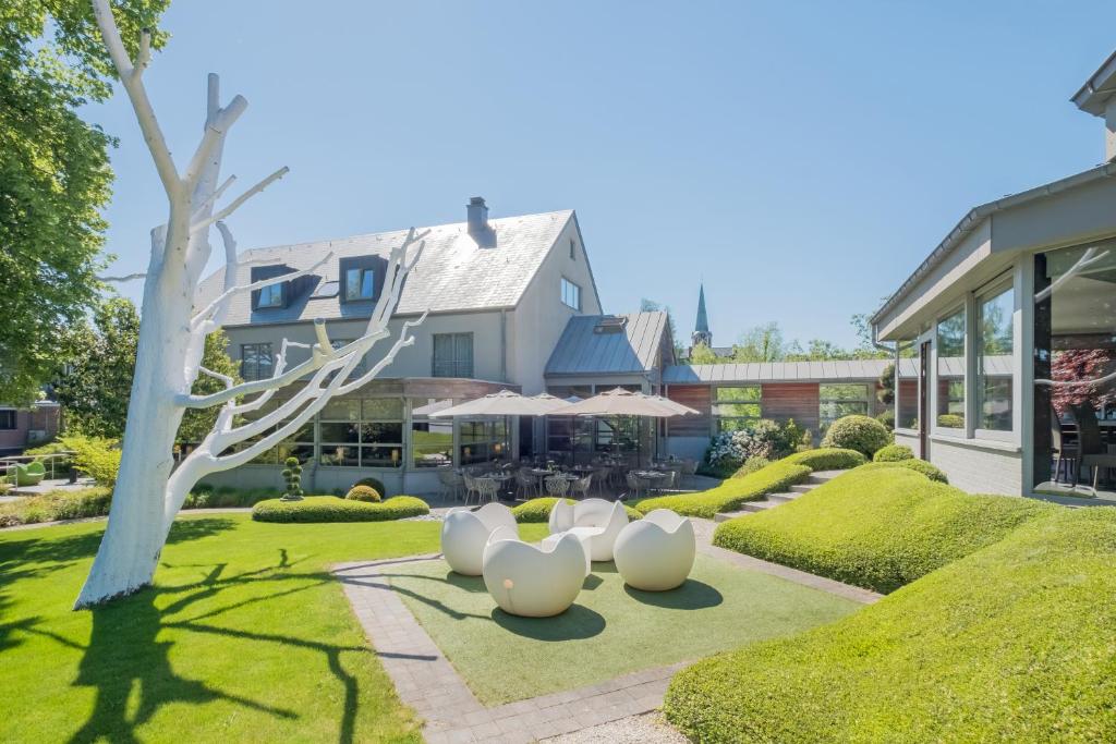 une maison avec quatre sculptures blanches sur la pelouse dans l'établissement Le Côté Vert, à Waterloo