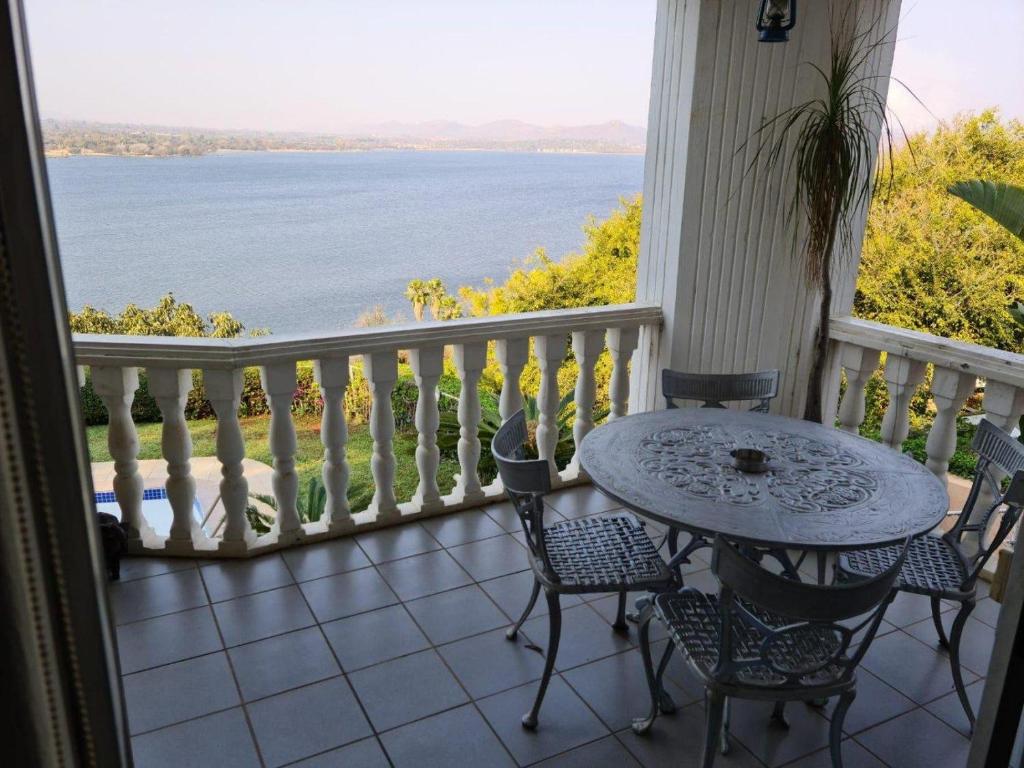 een tafel en stoelen op een veranda met uitzicht op het water bij Kosmos View Luxury Apartments in Hartbeespoort