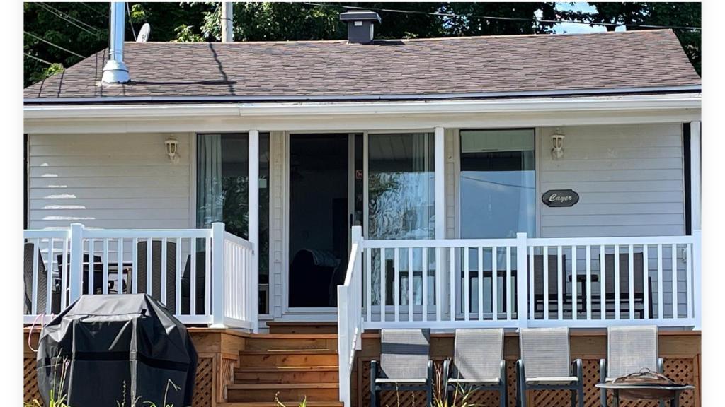 a house with a porch with a white railing at Chalets Plage St-Jean 2 in Saint-Jean