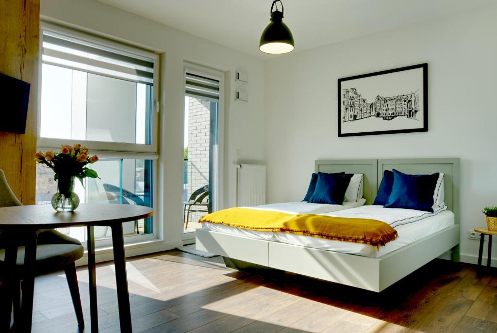 sypialnia z łóżkiem z niebieskimi poduszkami i stołem w obiekcie Essence Apartments Amber w Poznaniu