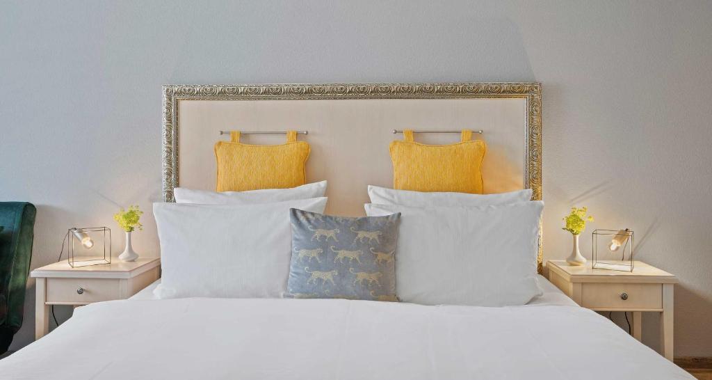 a bedroom with a white bed with yellow pillows at Hotel St Leonhard in Bad Griesbach