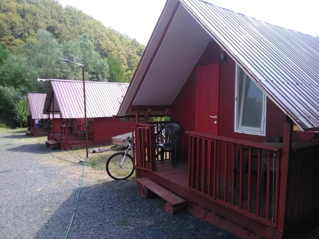 eine rote Hütte mit einem Fahrrad daneben geparkt in der Unterkunft La casuta de pe vale in Brănişca
