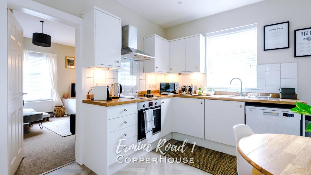 a kitchen with white cabinets and a table at Designer apartments for City Breaks in Chester in Chester