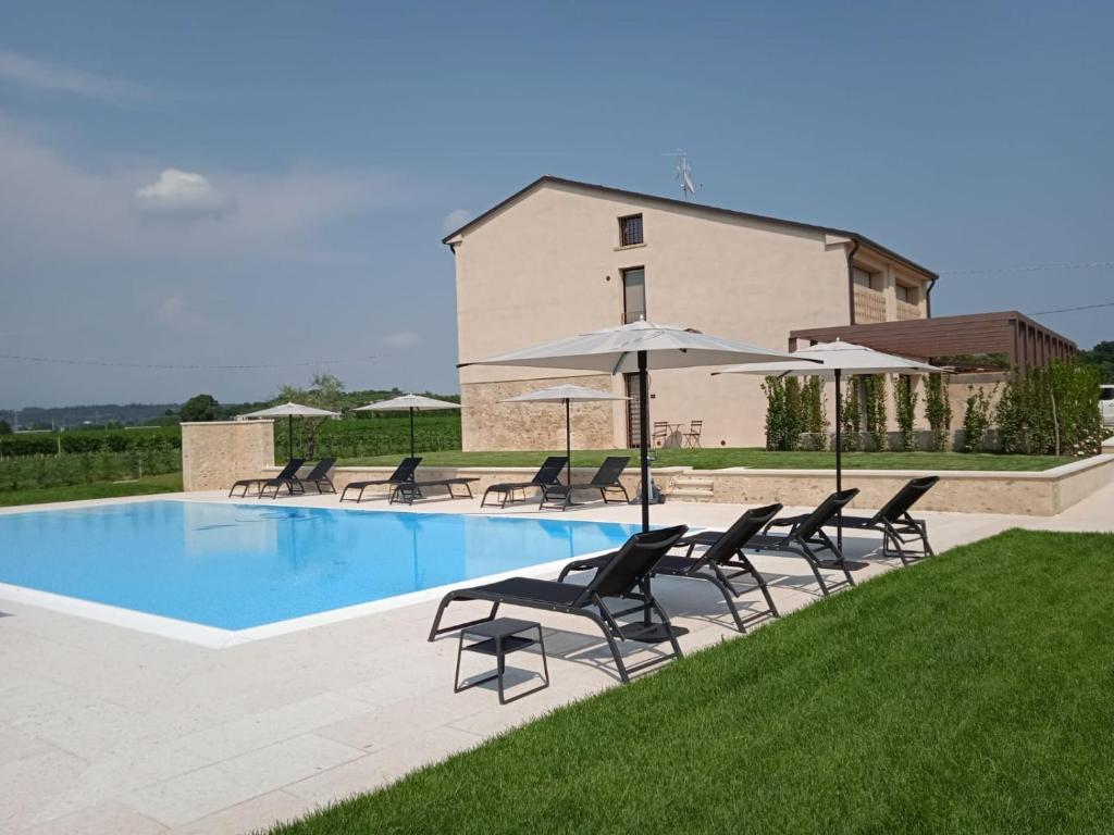 a pool with chairs and umbrellas in front of a building at agriturismo Casa Pezzo in Castelnuovo del Garda