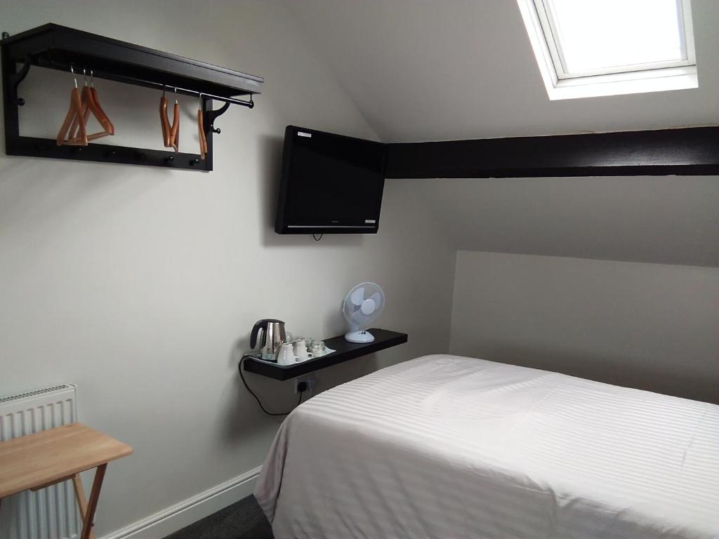 a bedroom with a bed and a tv on the wall at Comfort Guest House in Leicester