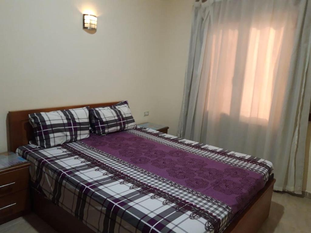 a bedroom with a bed with a purple comforter and a window at Hurghada Comfort Apartments in Hurghada