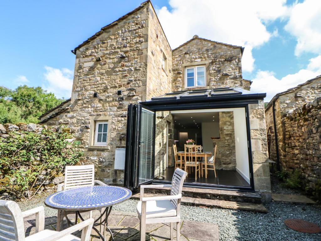 una extensión a una casa de piedra con mesa y sillas en Wayside Cottage, en Skipton