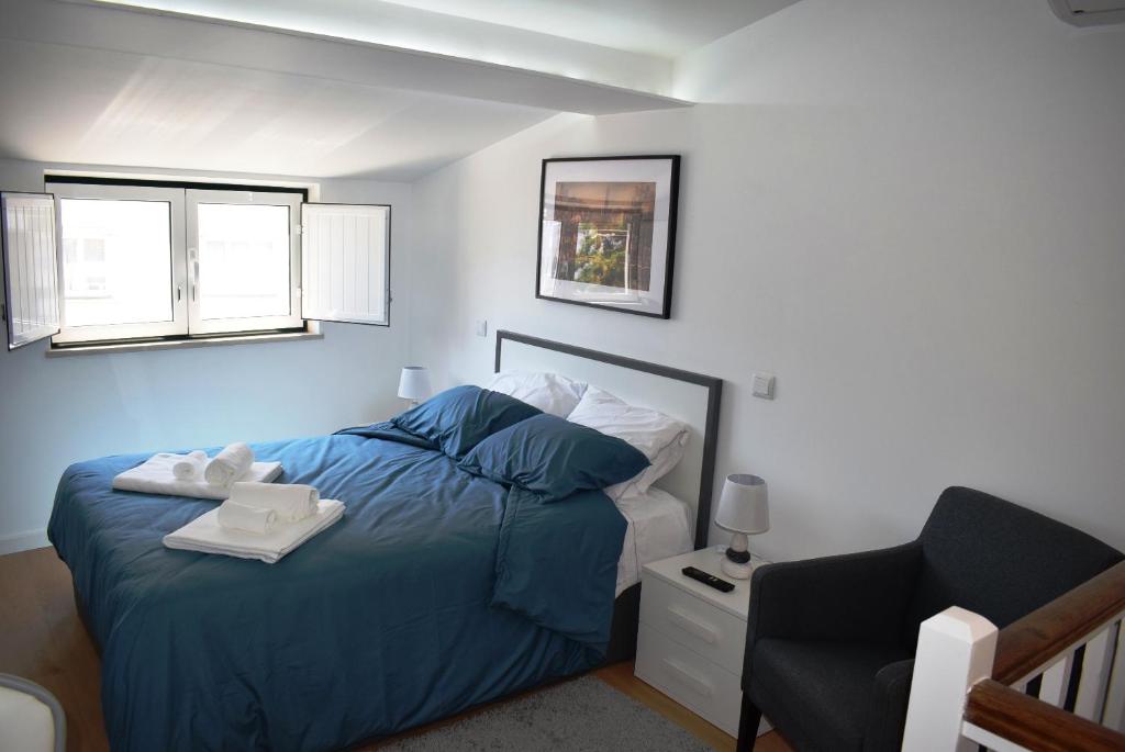 a bedroom with a blue bed and a chair at Studio Station 3 in Coimbra