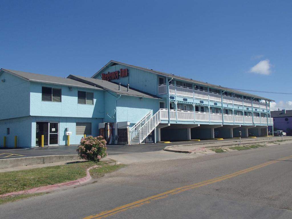 a building with a parking lot next to a street at Regency Inn Motel by the Beach in Corpus Christi