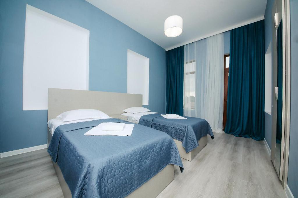 two beds in a room with blue walls at Plagio Green Terrace Homes in Kutaisi