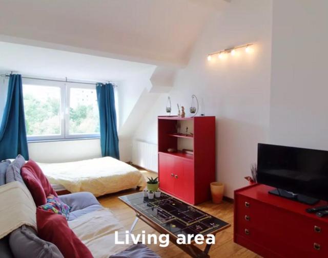 uma sala de estar com mobiliário vermelho e uma área de estar em Studio Cosy à Woluwé em Bruxelas