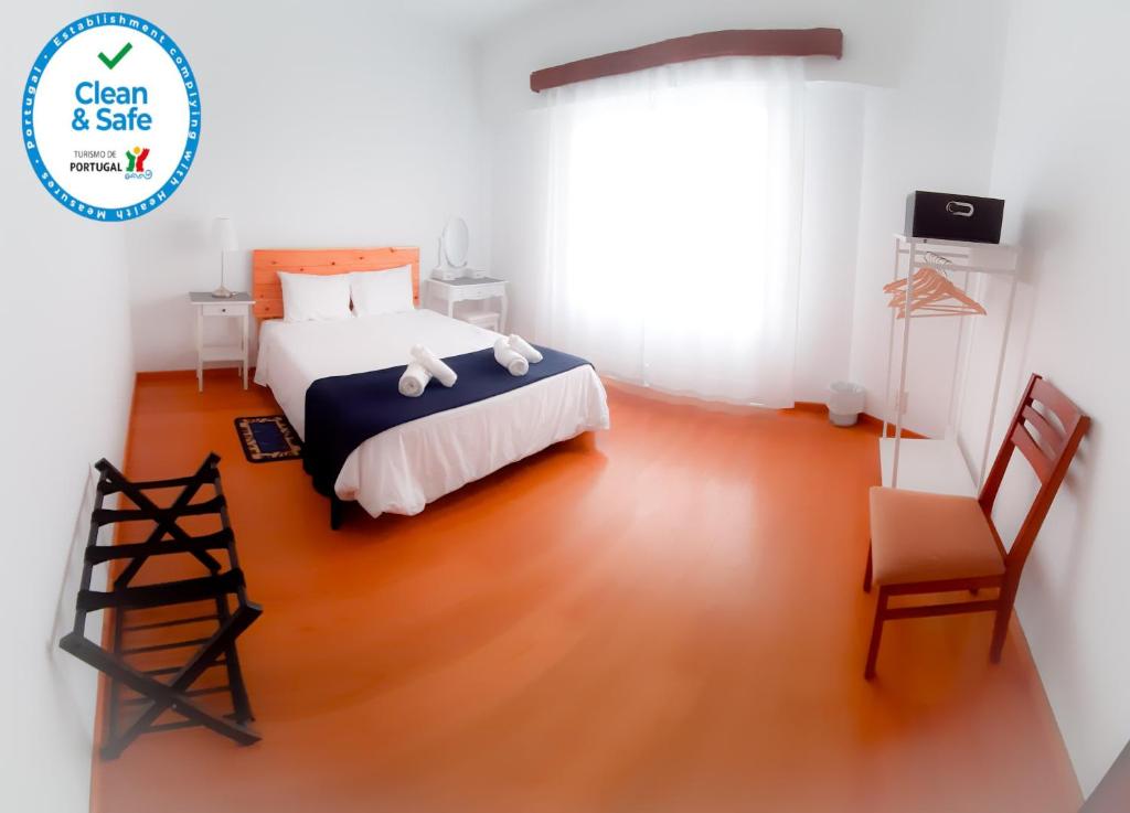 a bedroom with a bed and a chair at Adamas Bed & Breakfast in Ponta Delgada
