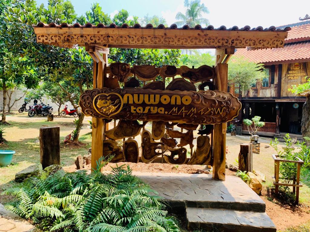 un banc en bois dans un parc avec un panneau dans l'établissement Nuwono Tasya Syariah, à Bandar Lampung