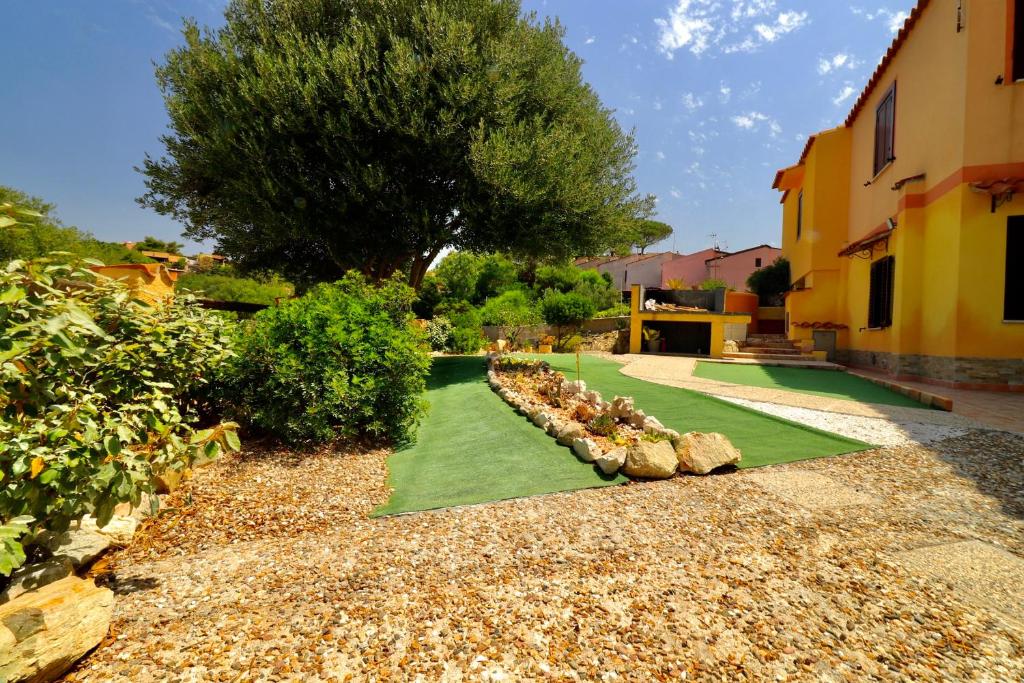 a garden with grass and rocks and a tree at Appartamento Torre 82 in Torre Dei Corsari
