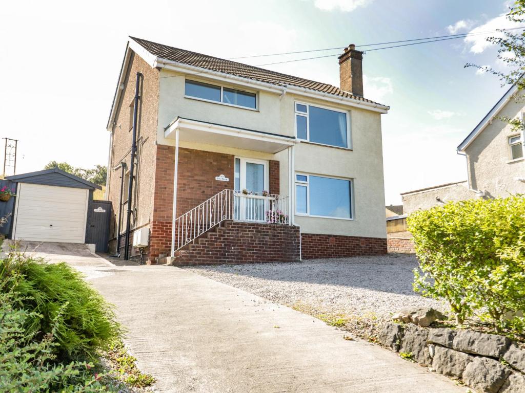 una casa de ladrillo con ventanas azules y entrada en The Nook 285B, en Colwyn Bay