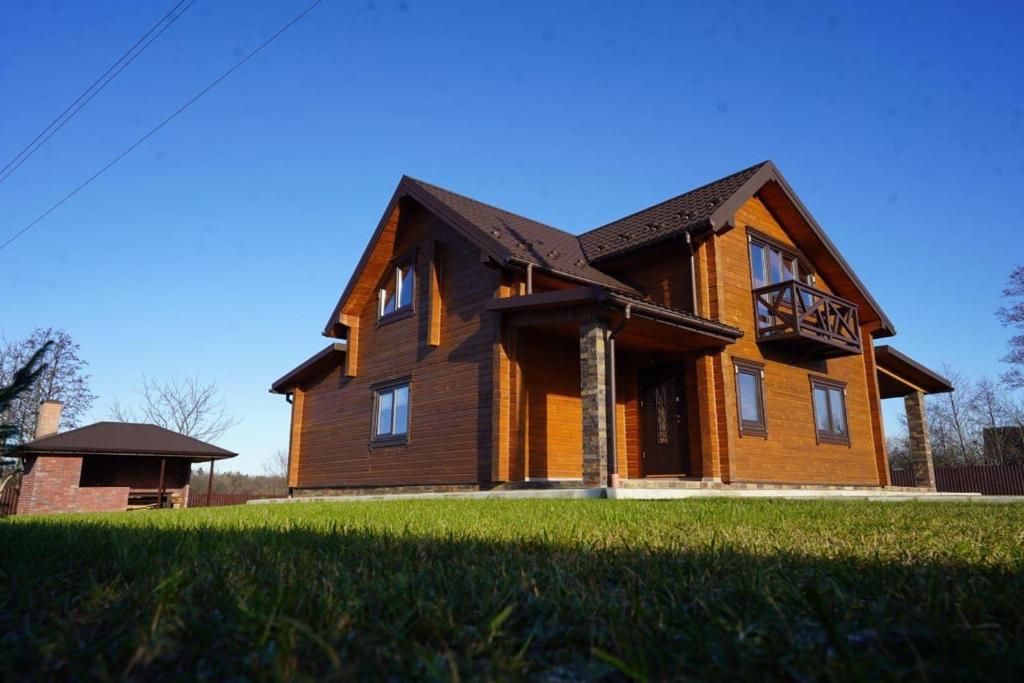 a large wooden house on a grass field at Villa Family House Truskavets in Modrychi