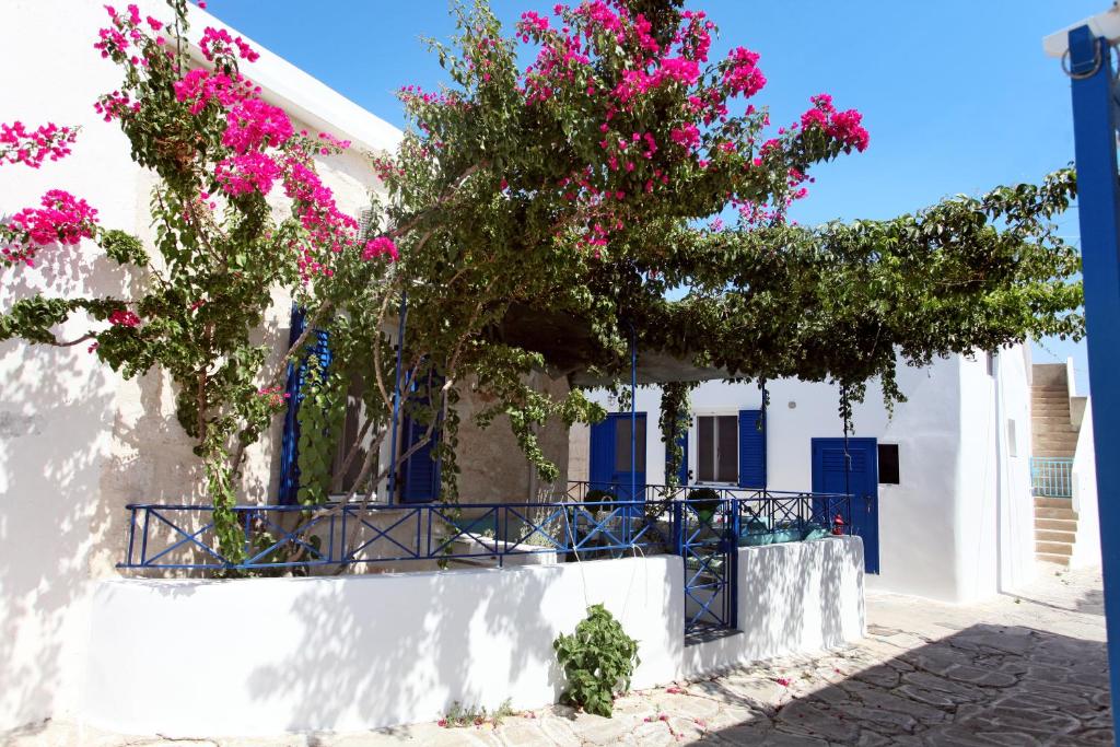 a white building with blue doors and pink flowers at Archipelagos Kimolos in Kimolos