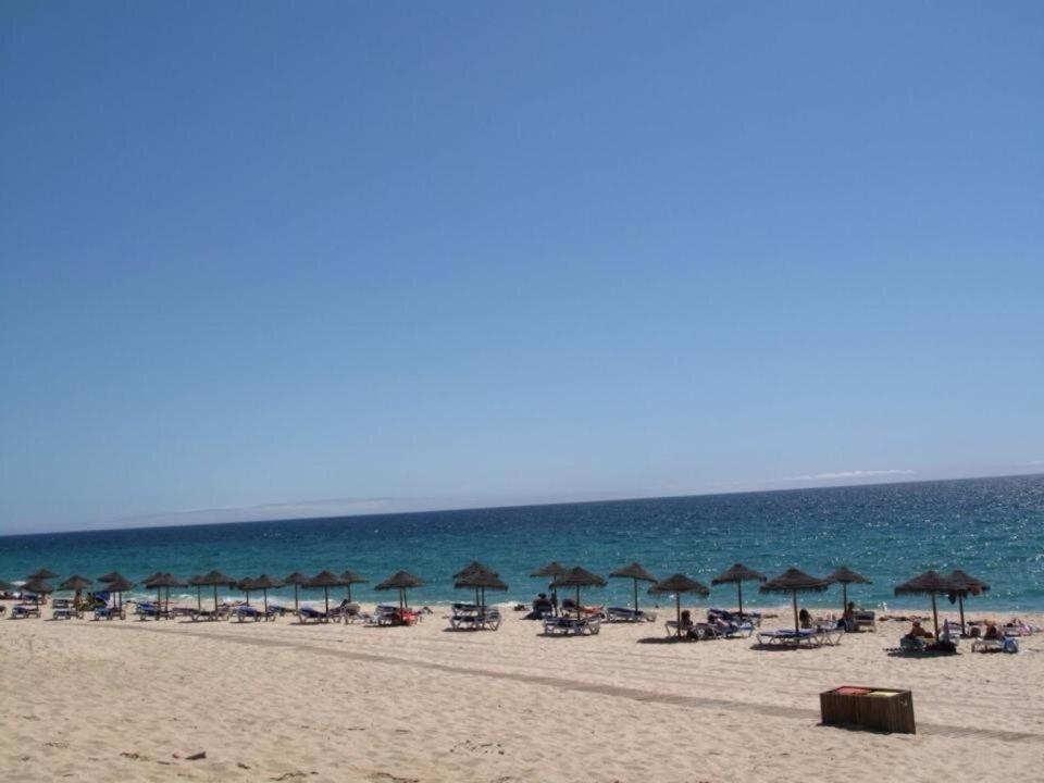 una playa con sombrillas y sillas y el océano en SolTroia - Casa do Pinheiro, en Tróia