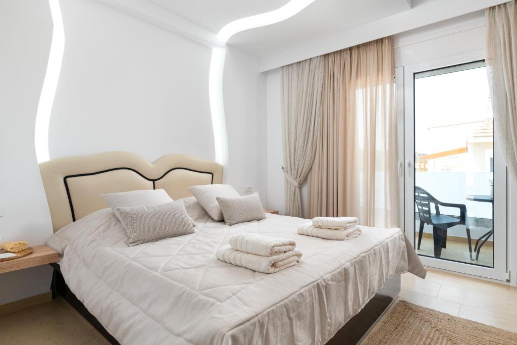 a white bedroom with a bed with towels on it at White House Kokas Luxury Apartments in Kremasti