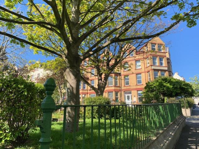 a fence in front of a building with a tree at Arrandale House in Douglas