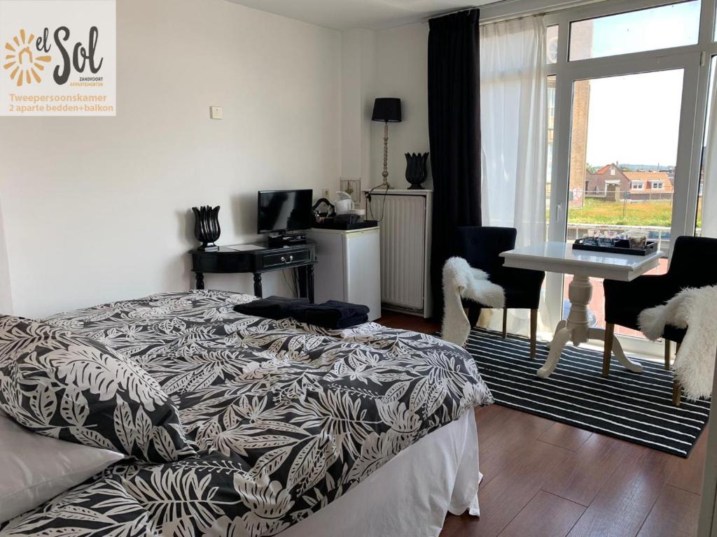 een slaapkamer met een bed, een bureau en een raam bij El Sol Zandvoort 2 in Zandvoort