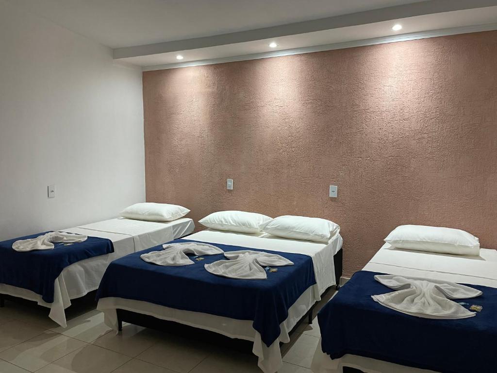 drie bedden in een kamer met handdoeken erop bij Pousada Império de Minas in Capitólio