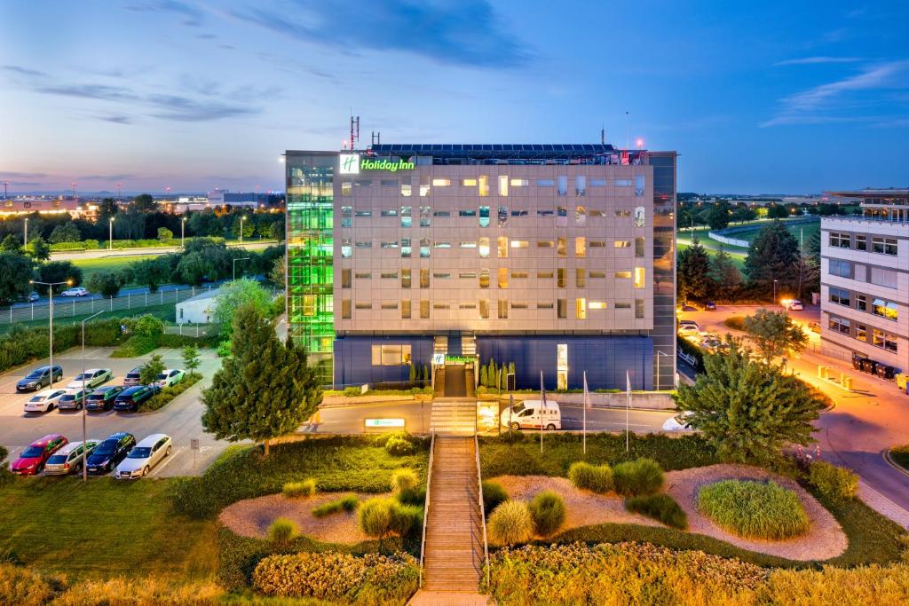 a building with a fountain in front of a parking lot at Holiday Inn Prague Airport, an IHG Hotel in Prague