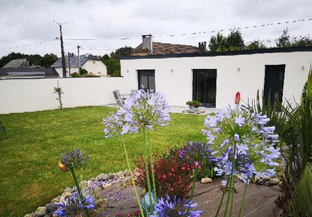 un jardin avec des fleurs violettes en face d'une maison blanche dans l'établissement MAISON DU GABAS D'ANNA & ROSE, à Limendous