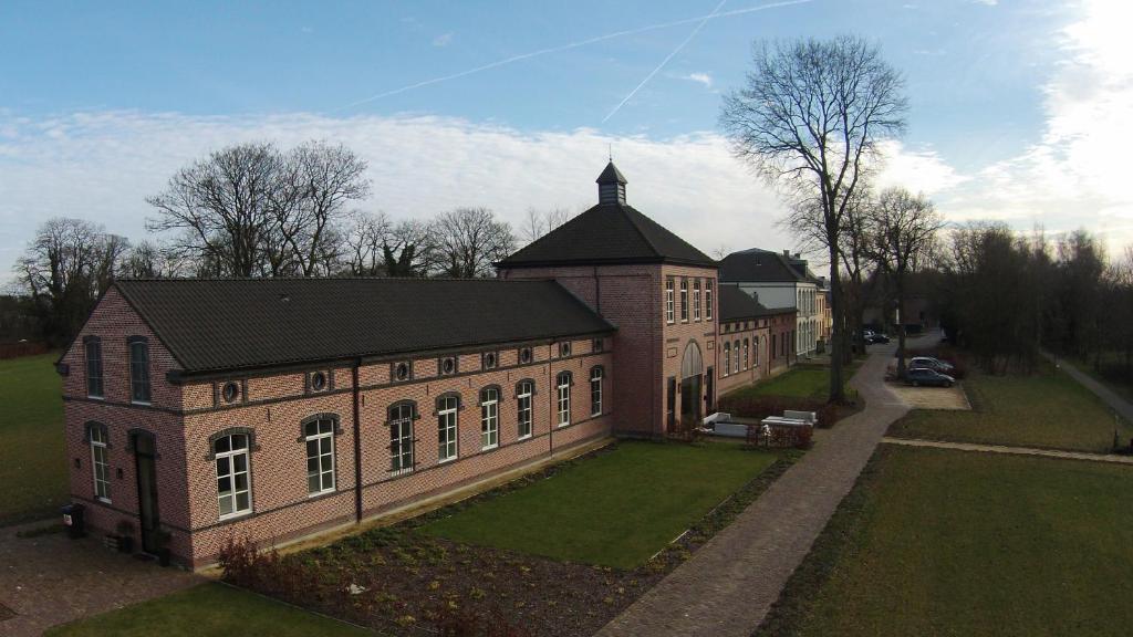 a large brick building with a black roof at Factorij10 in Peer