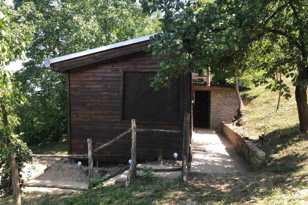 un pequeño edificio de madera con una puerta en un campo en Odmor za dušu i tijelo u srcu prirode, en Aljmaš