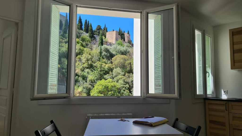 Cette chambre dispose d'une table et d'une fenêtre avec vue sur la montagne. dans l'établissement CASSIS CENTRE Magnifique Appartement à 2 mn de la plage et du Port, tous les commerces à proximité idéalement placé, à Cassis
