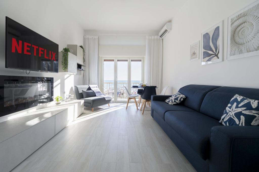 uma sala de estar com um sofá azul e uma televisão em Nuovo Appartamento sulla spiaggia con larga terrazza di 70 mq e posto auto privato em Anzio